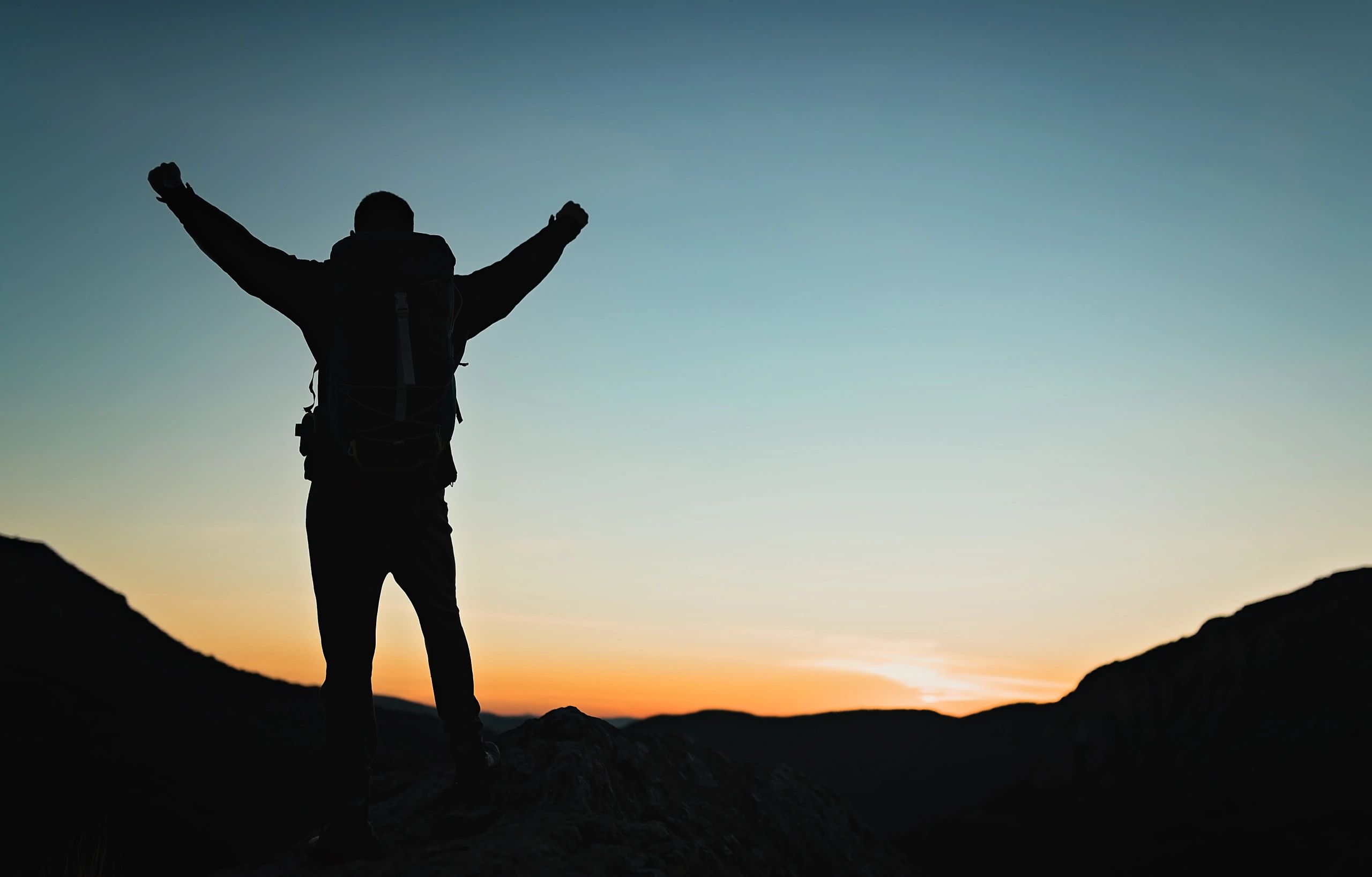 Silhouette at sunrise with arms raised, symbolizing transformation and renewal