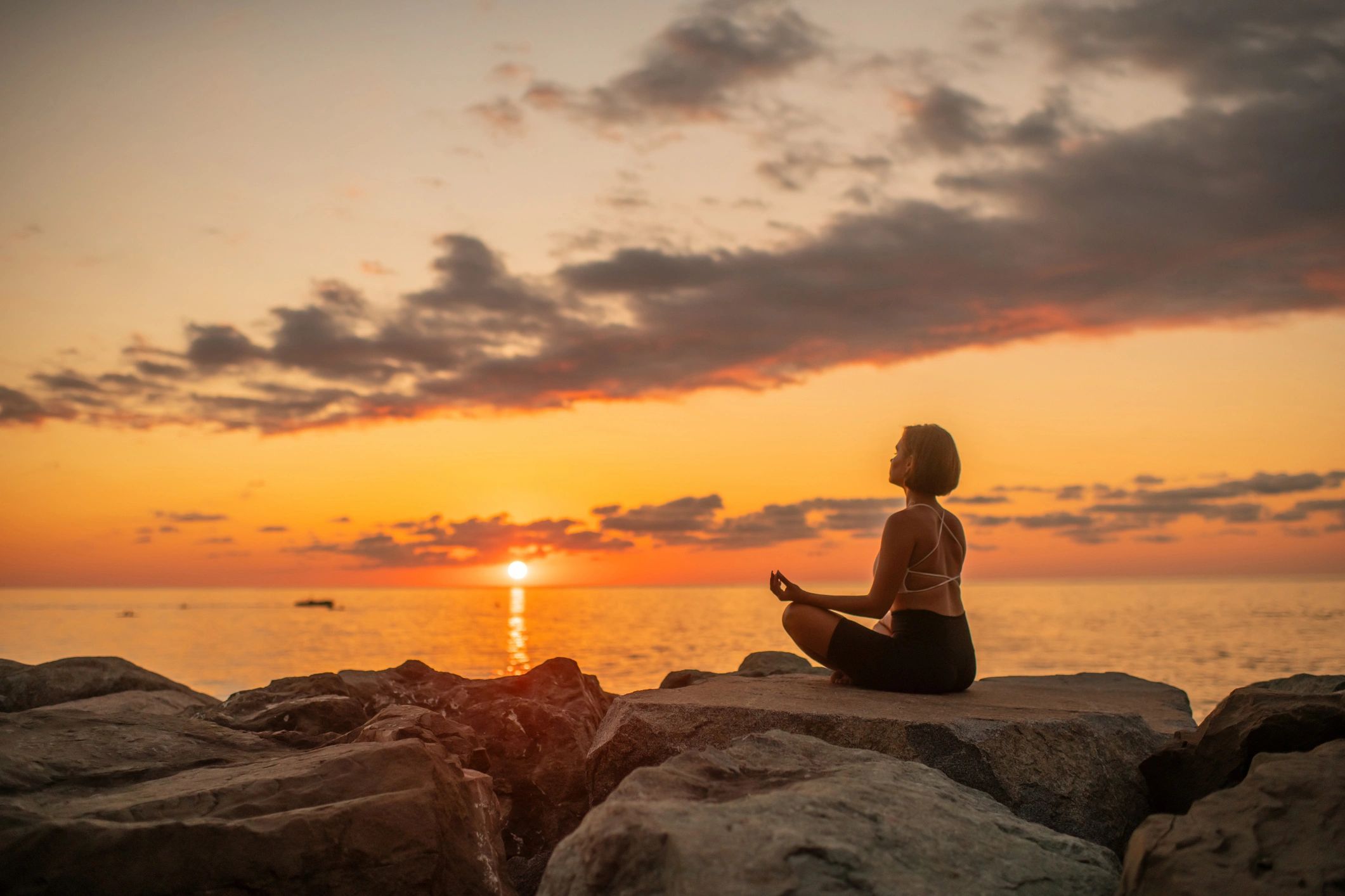 Person practicing meditation at sunset