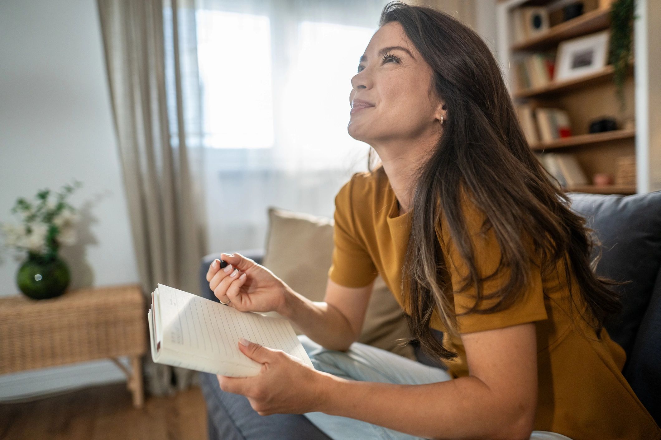 Woman journaling and reflecting in a cozy living room